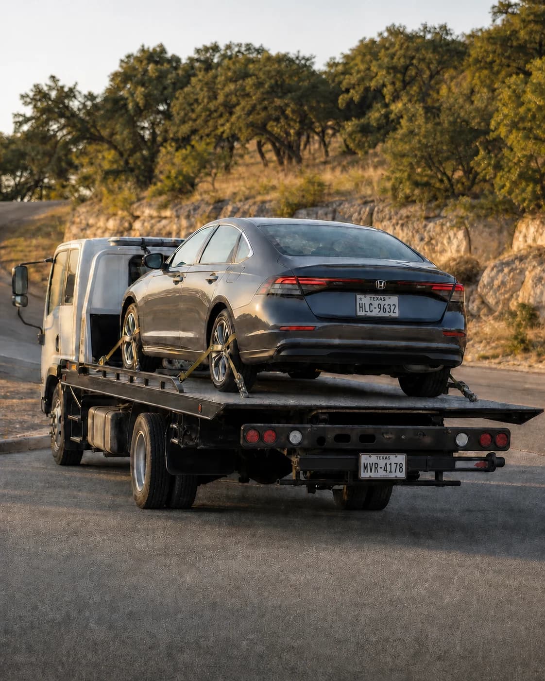 Gray sedan secured on a flatbed tow truck